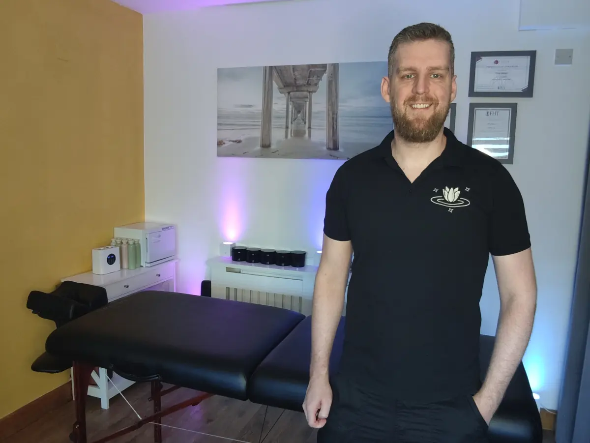 Rene Nemec standing beside the treatment table in his private massage studio in Old Trafford, Manchester.